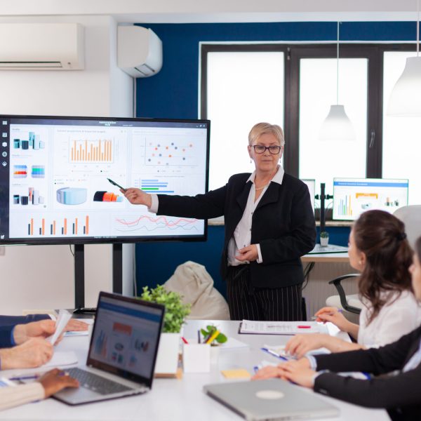 Senior woman company leader brainstorming in conference room Corporate staff discussing new business application with colleagues looking at screen