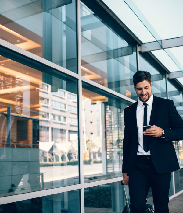 Happy,Young,Businessman,Walking,And,Looking,At,Mobile,Phone,At